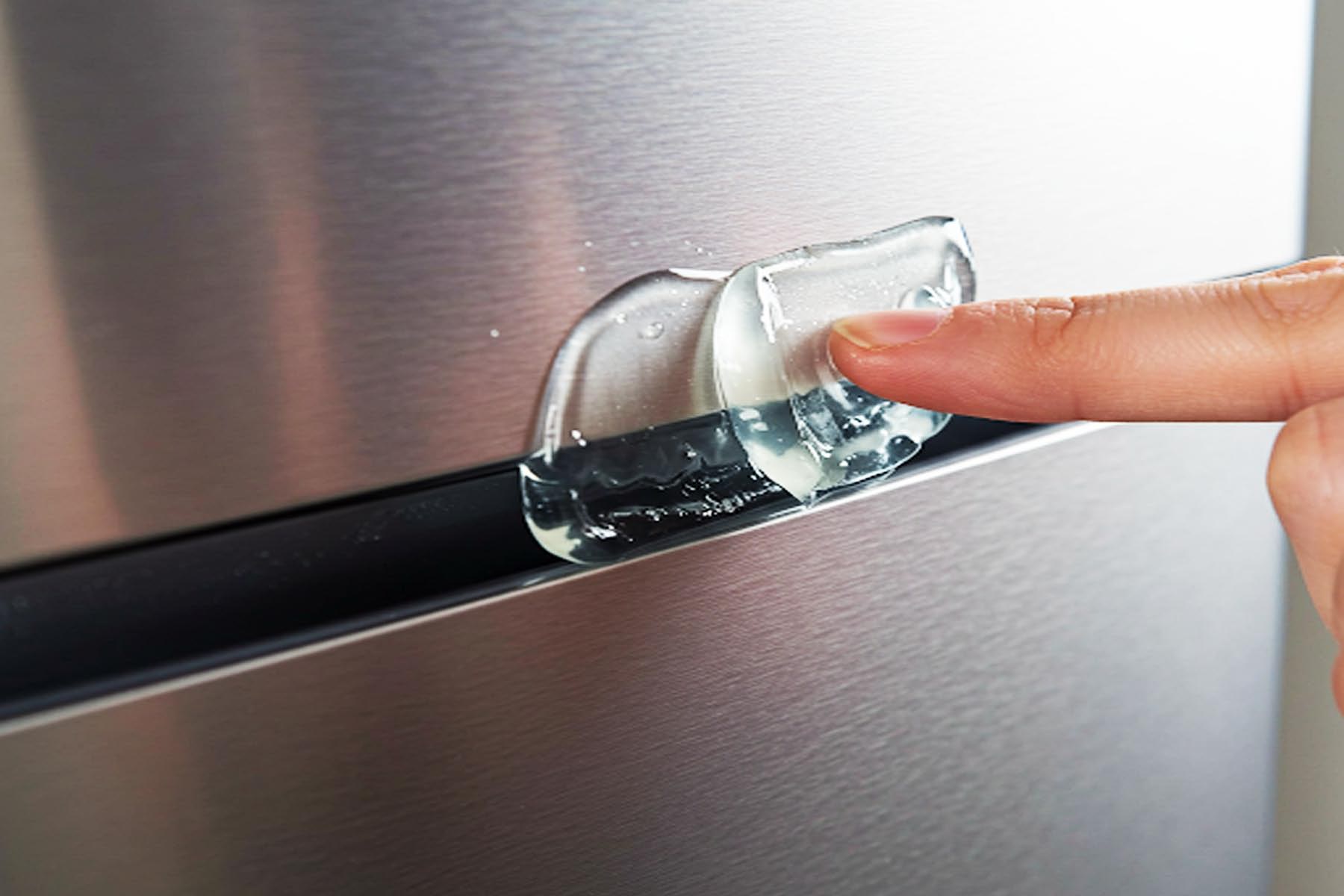 Close-up of a refrigerator door seal being lubricated with food-grade silicone grease to maintain an airtight seal.